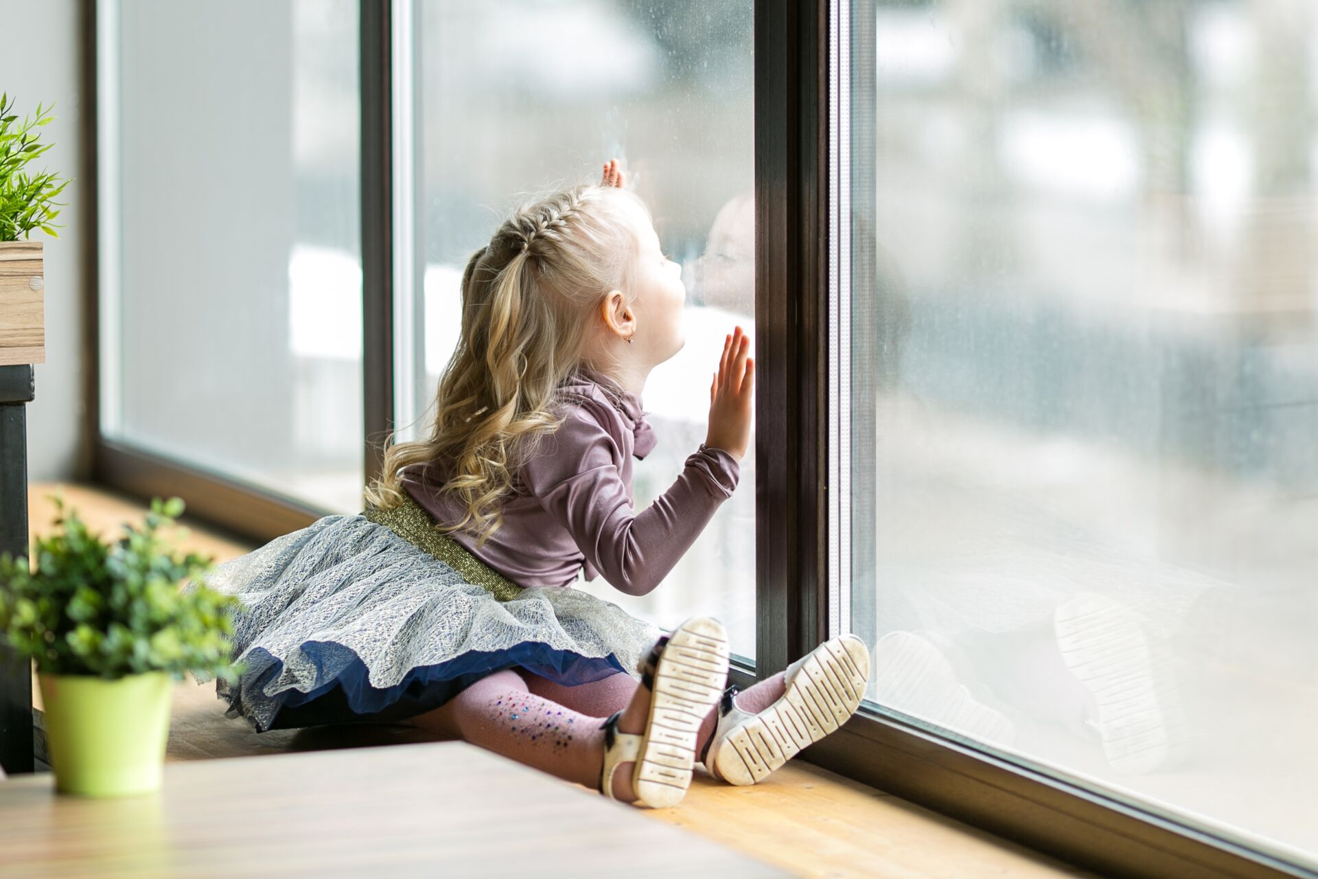 Ein Bild eines kleinen Kindes, das auf einer Fensterbank sitzt und aus dem Fenster schaut