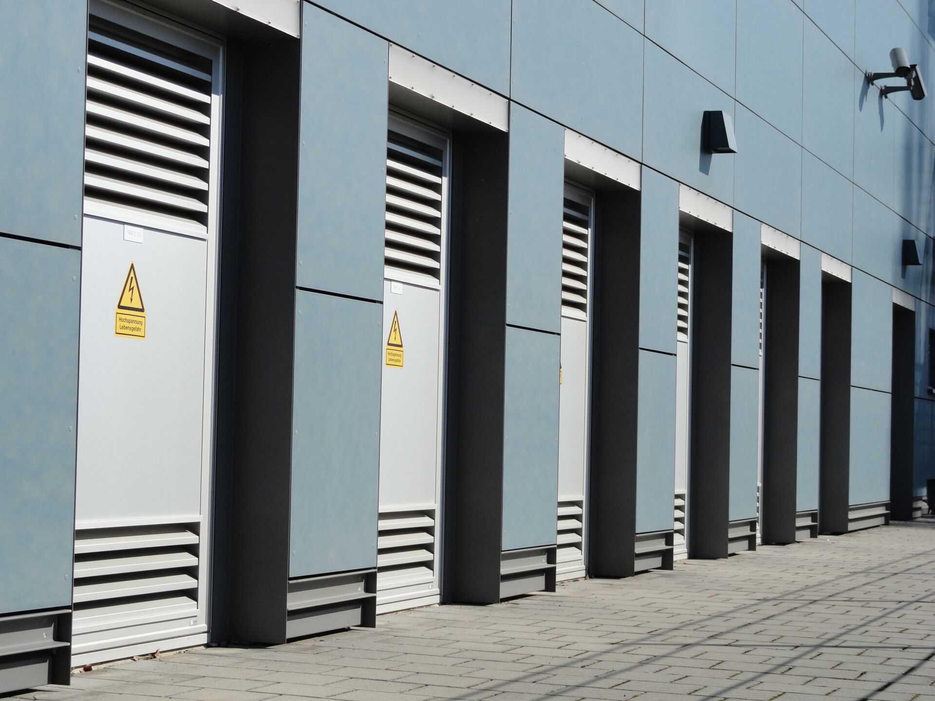 Eine Reihe von Sondertüren mit Lüftungsgittern in einer Fassade.